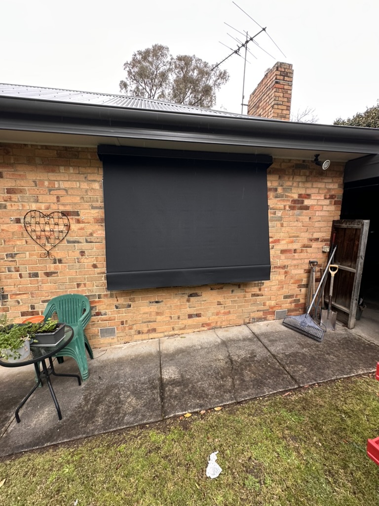 Single charcoal auto awning on a backyard brick wall