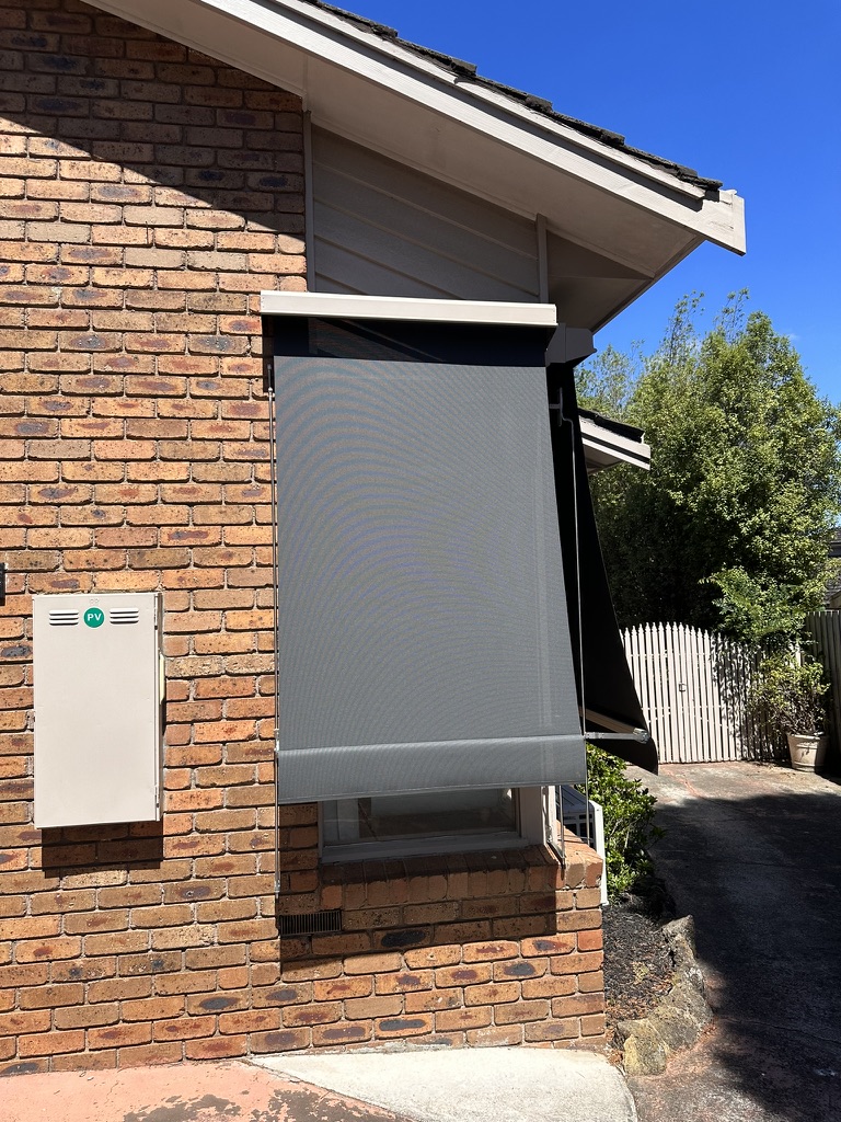 Grey auto awning projected from a brick window
