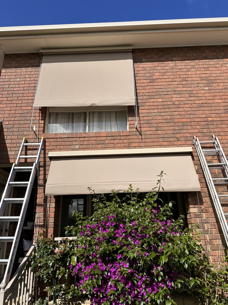 Cream auto awnings on upper and lower brick windows