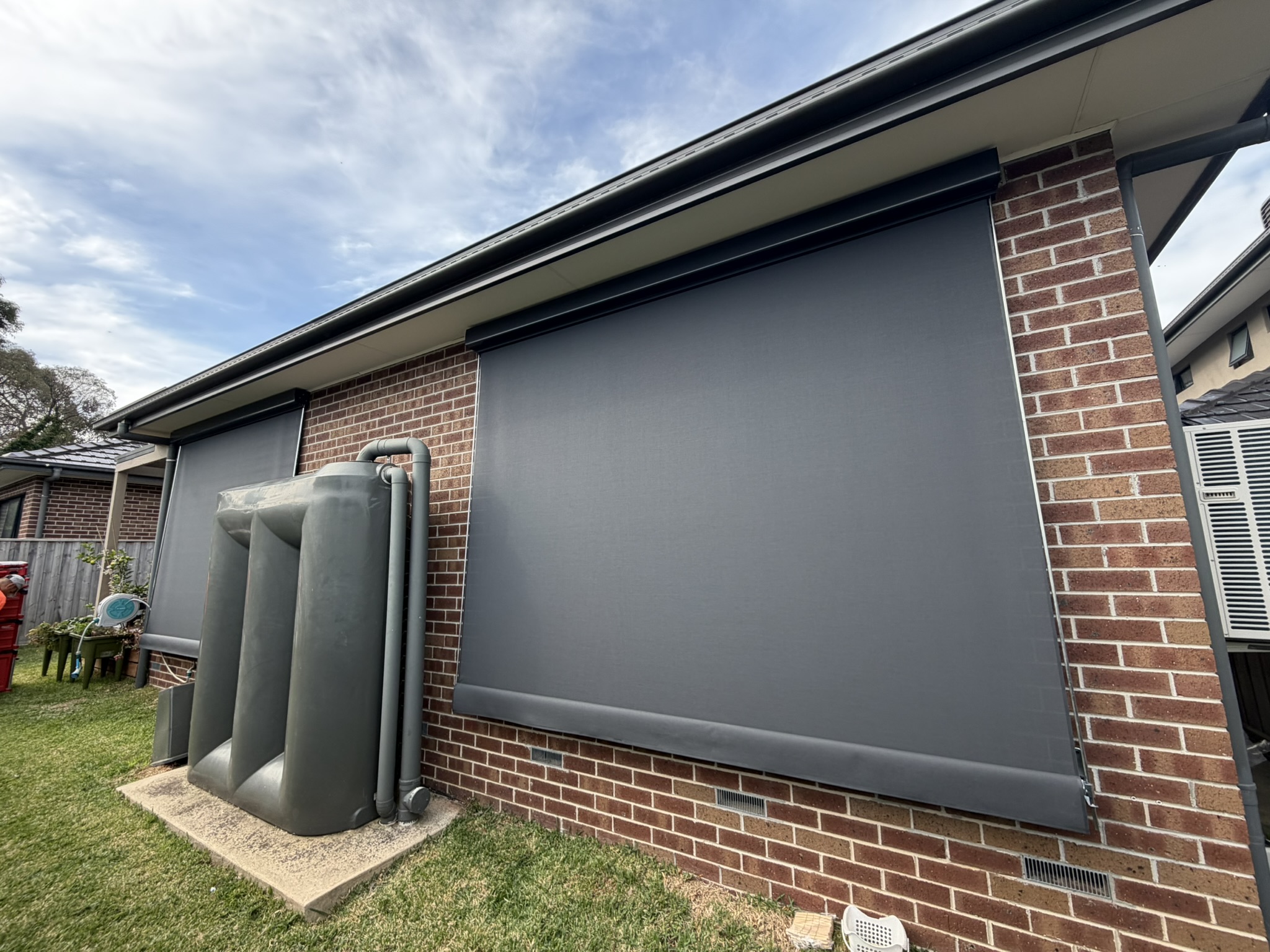 Charcoal fixed guide awnings installed on a brick home