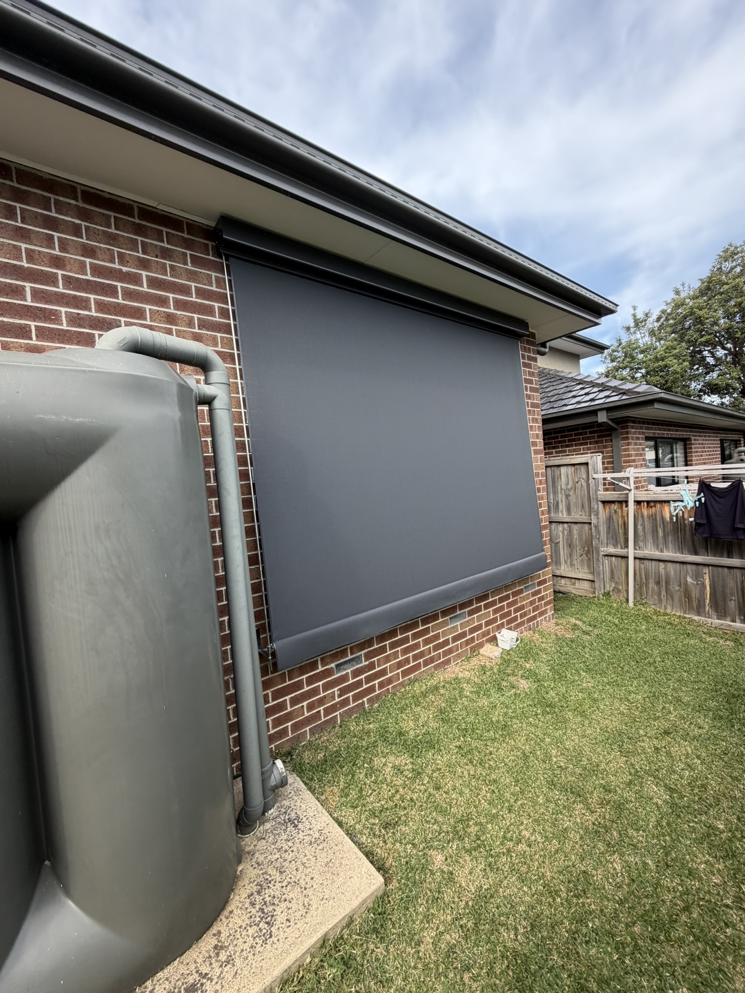 Close-up of a charcoal fixed guide awning beside a rainwater tank