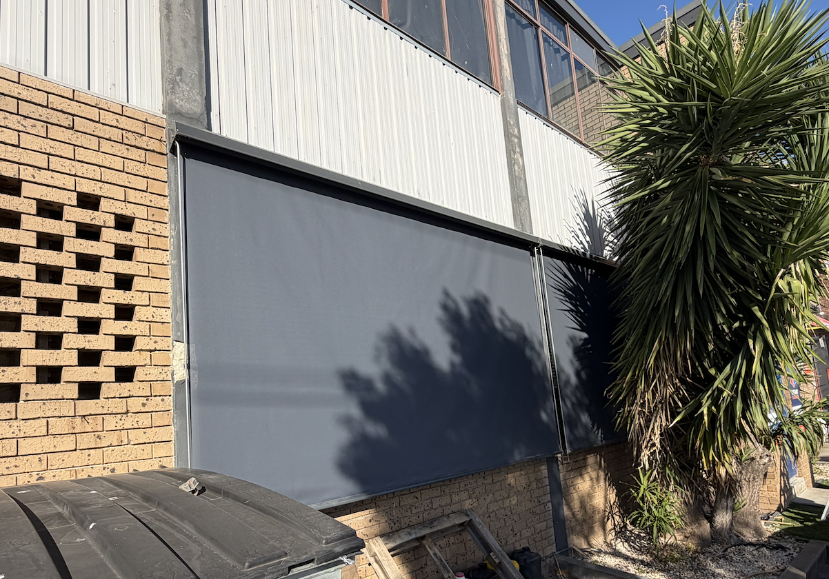 Wide charcoal fixed guide awning on a commercial brick facade