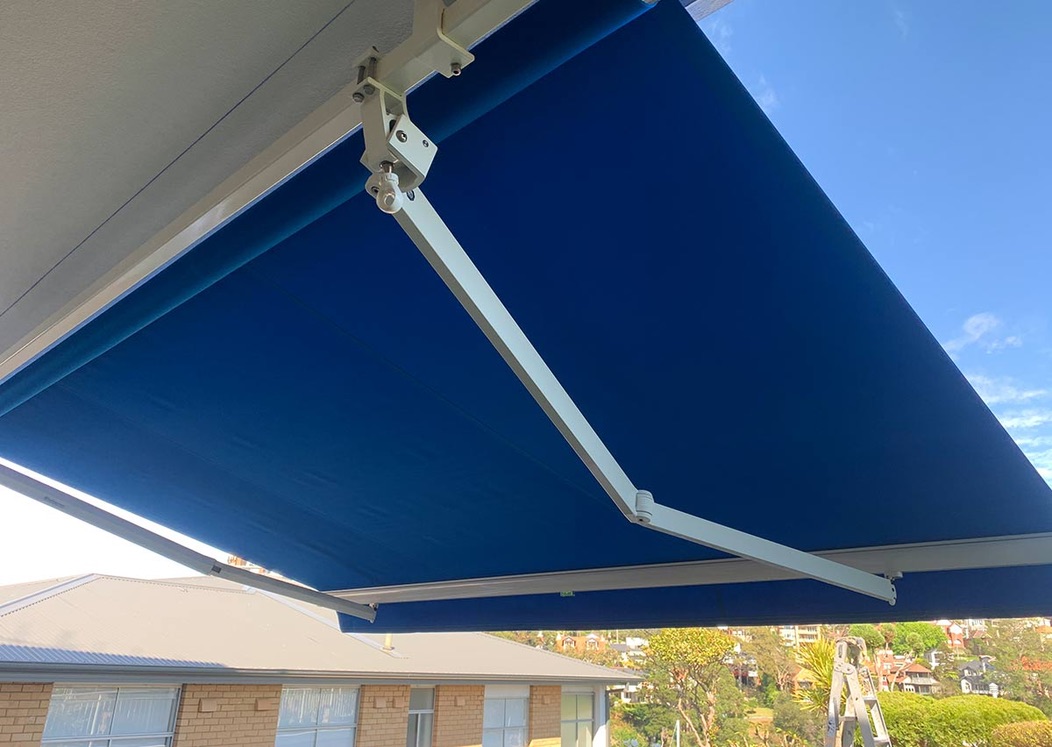 Blue folding arm awning showing articulated arm mechanism