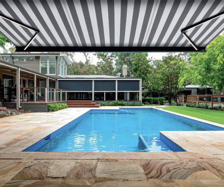Striped folding arm awning shading a pool terrace