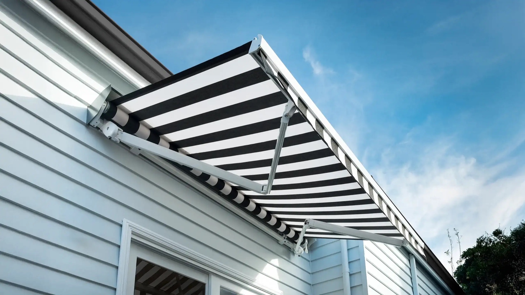 Striped folding arm awning showing articulated arms and fabric projection