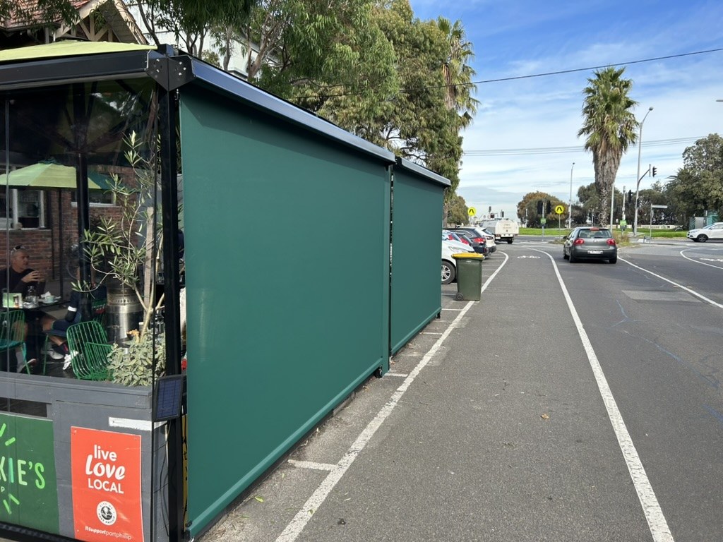 Green mesh straight drop blinds on the street side of Frankie's Top Shop