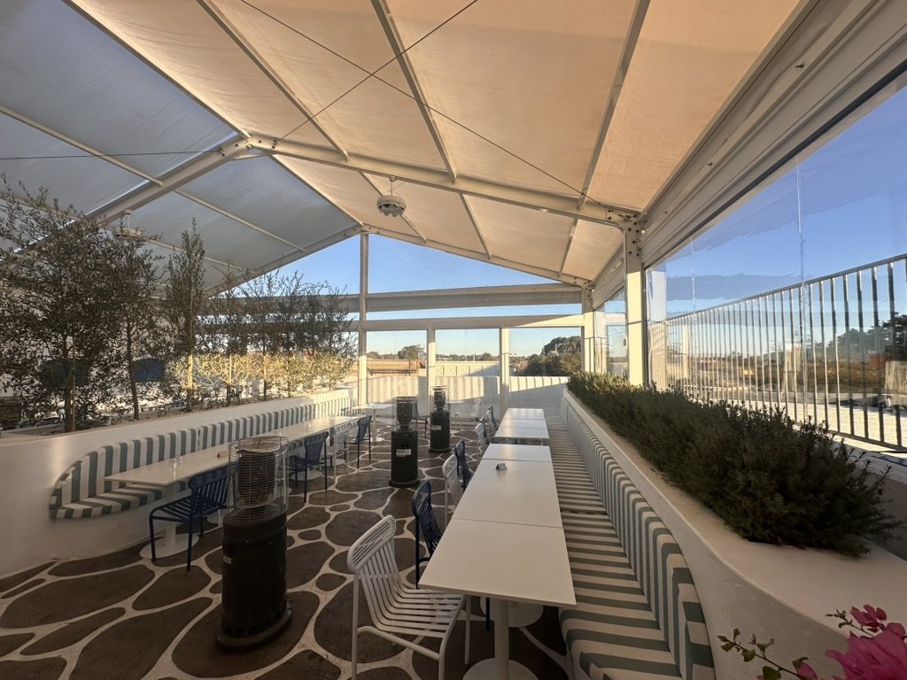 Motorised Clear PVC Ziptrak blinds and fixed panels enclosing the Olympia Restaurant rooftop dining area in Oakleigh