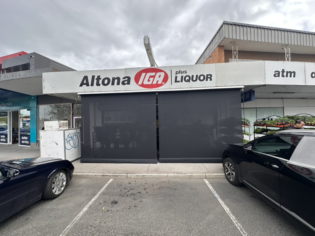 Dark mesh straight drop blinds across a retail frontage