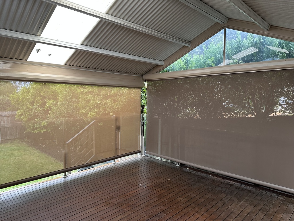 Light-coloured mesh straight drop blinds around a covered deck