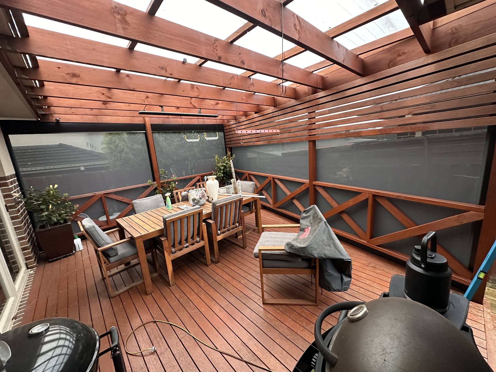 Dark solar mesh Ziptrak blinds fitted to a timber outdoor dining area