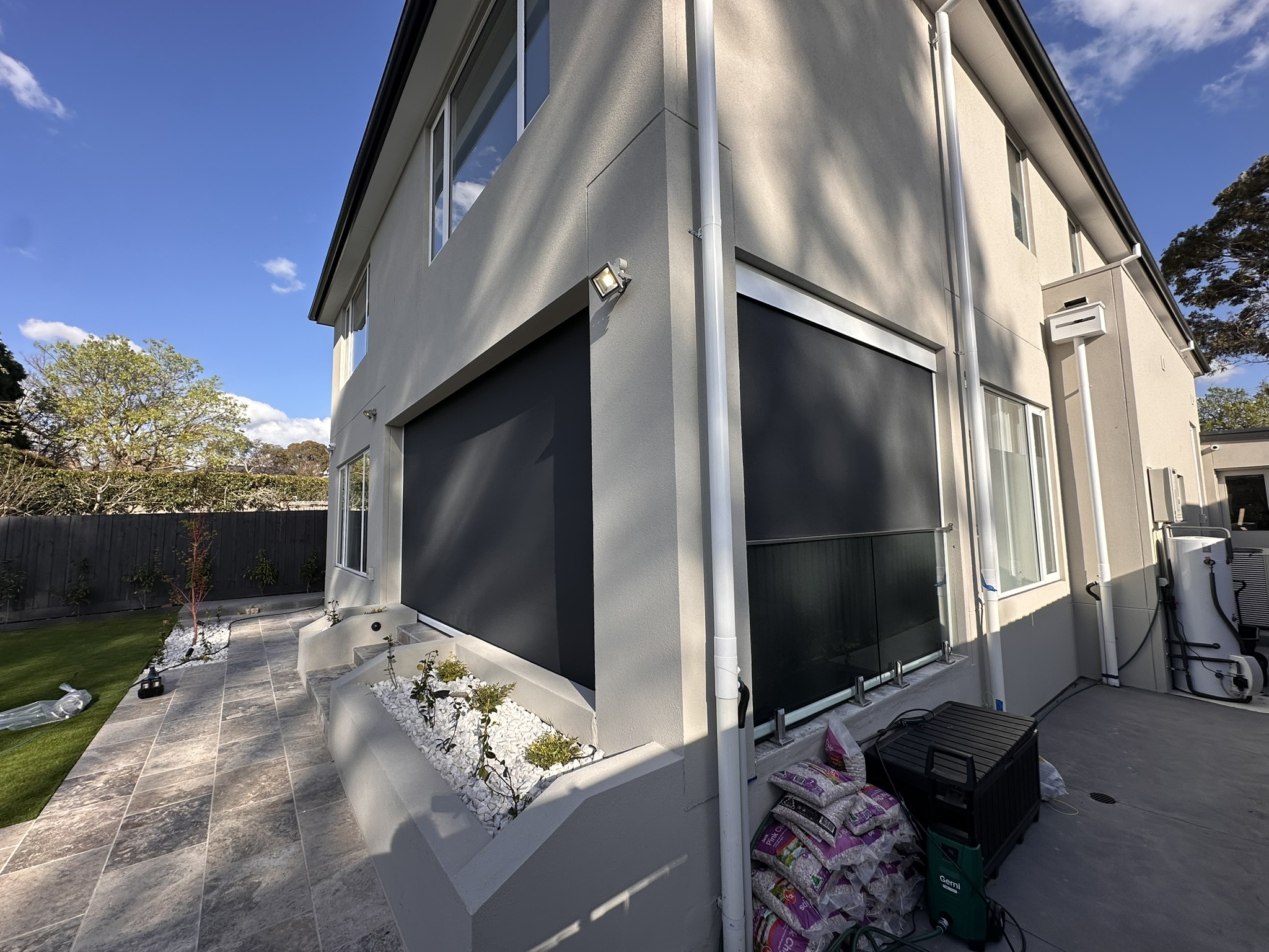 Dark mesh Ziptrak blinds fitted in front of large modern house windows
